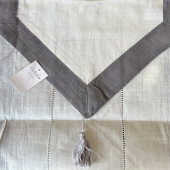 Zoom sur details du chemin de table, couleur blanc cassé, bordure grise et details au extremités.